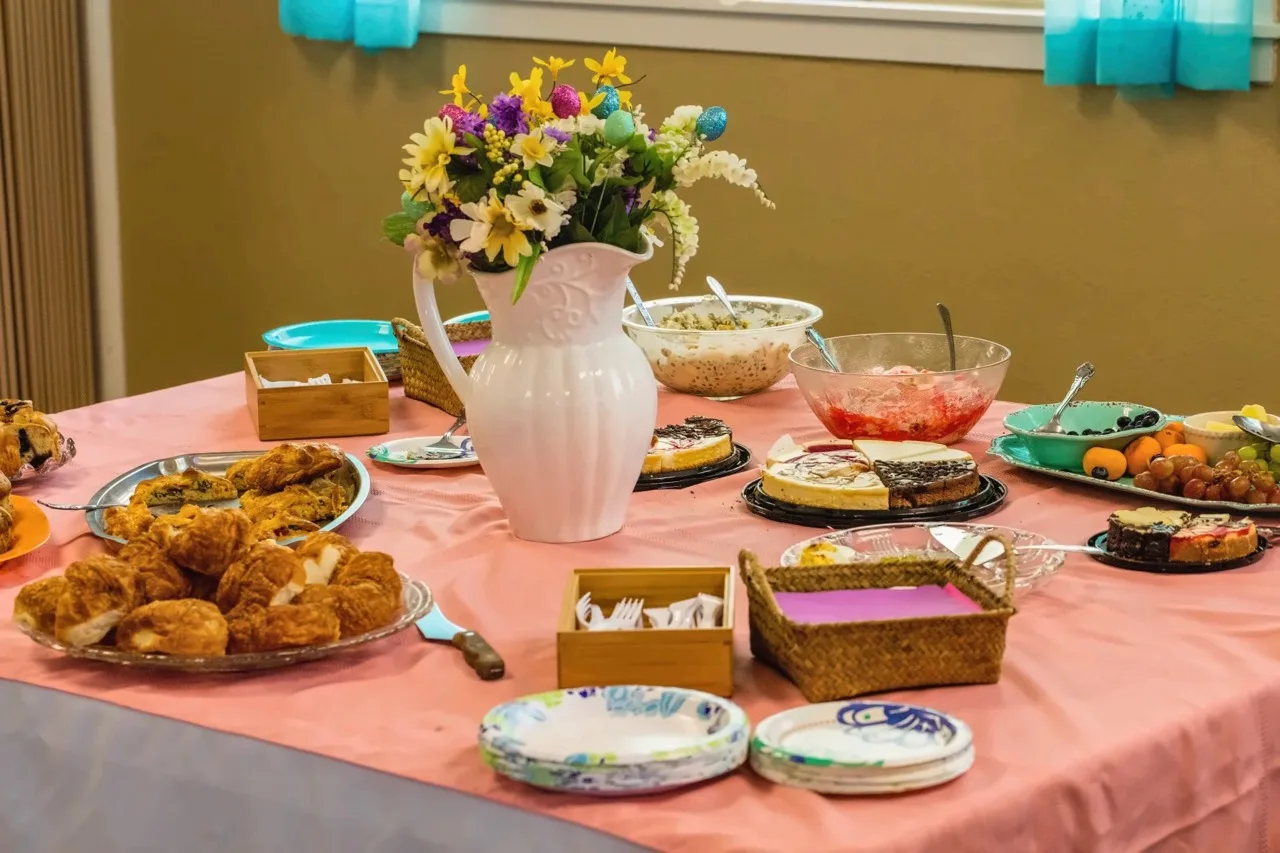 A fellowship table filled with homemade food and flowers after a church gathering