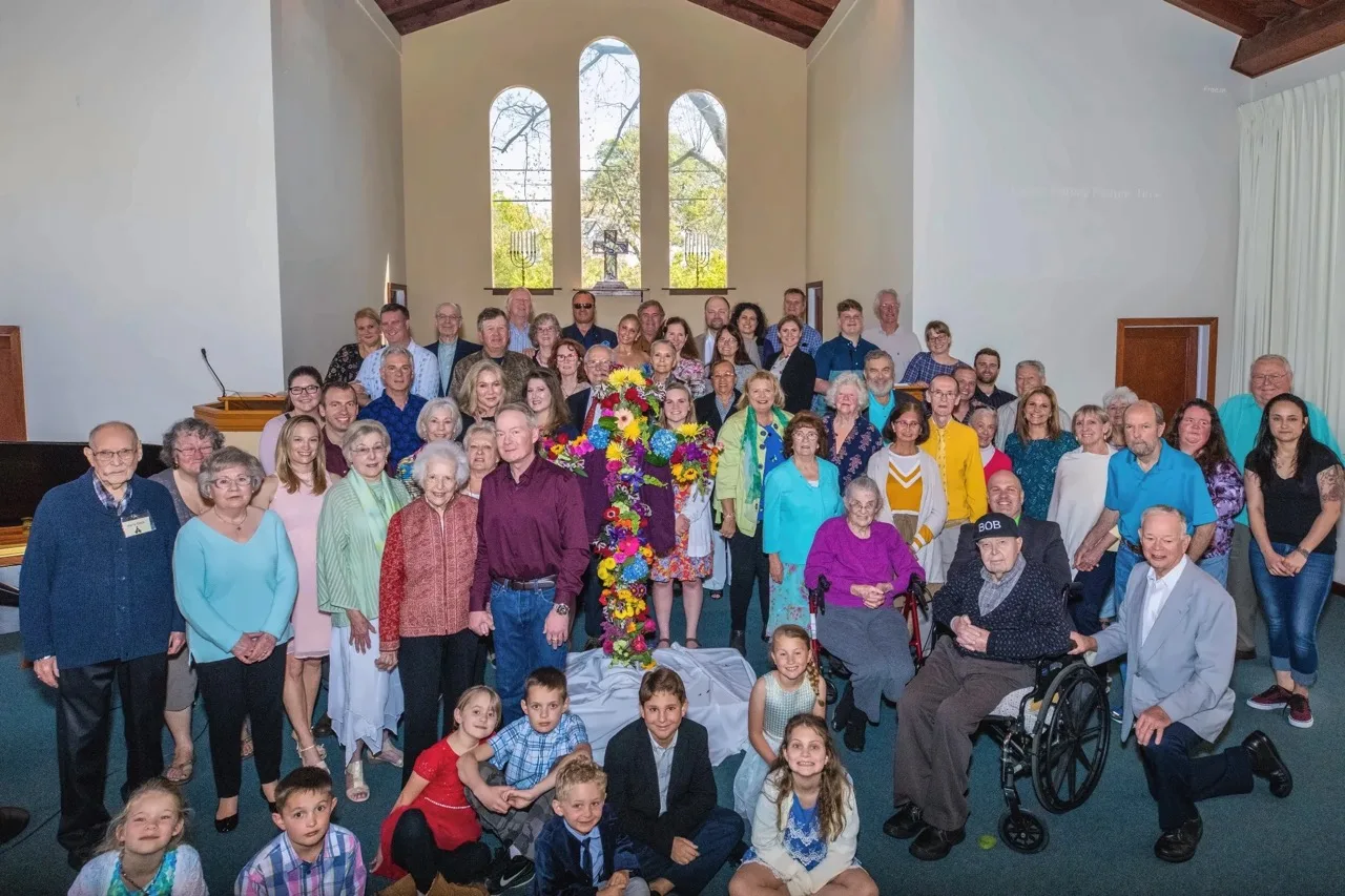 The whole Sonoma Valley Community Church family, all ages, gathered around the Easter flower cross in the sanctuary