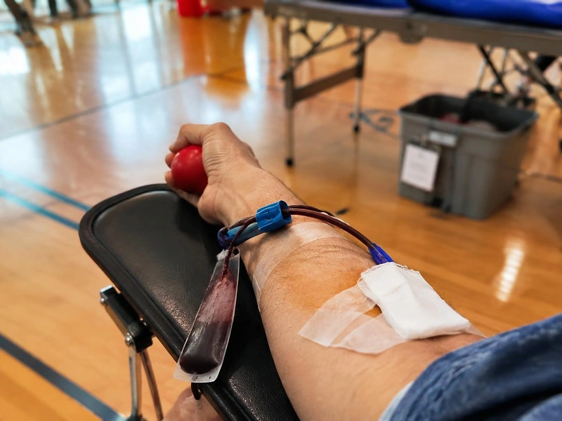 A blood drive donor giving blood at a donation chair